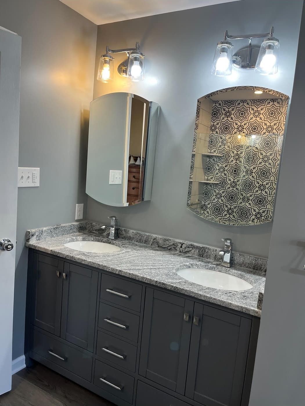Remodeled double vanity with arched mirrors and a tile accent niche