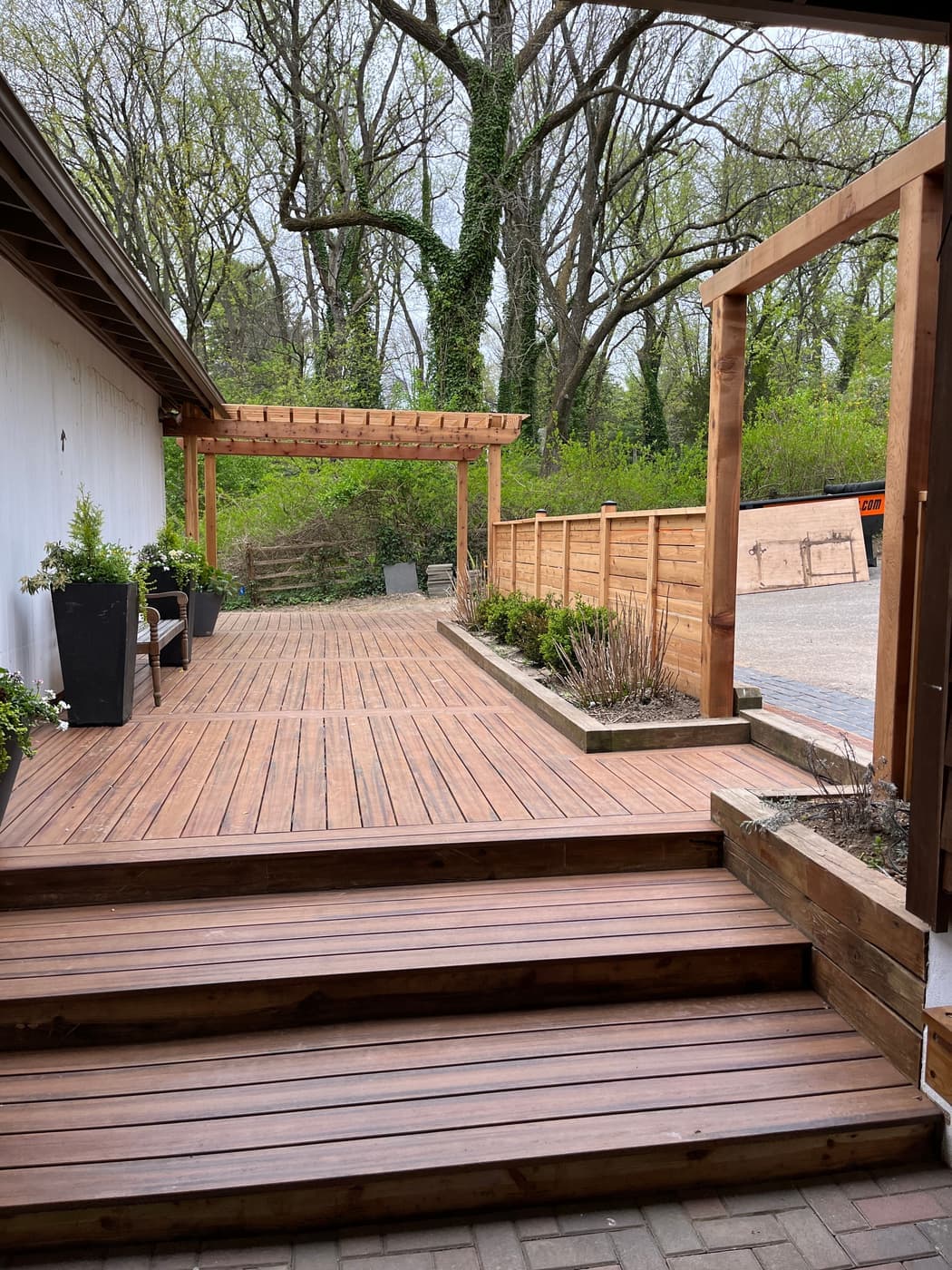 Wood deck with a cedar pergola in a wooded backyard