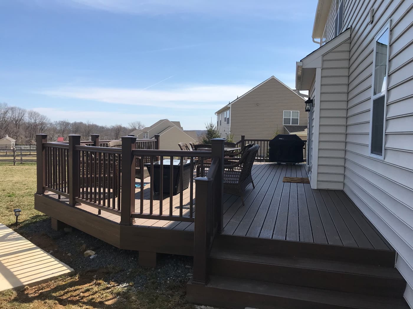 Brown composite deck with matching railing and patio furniture