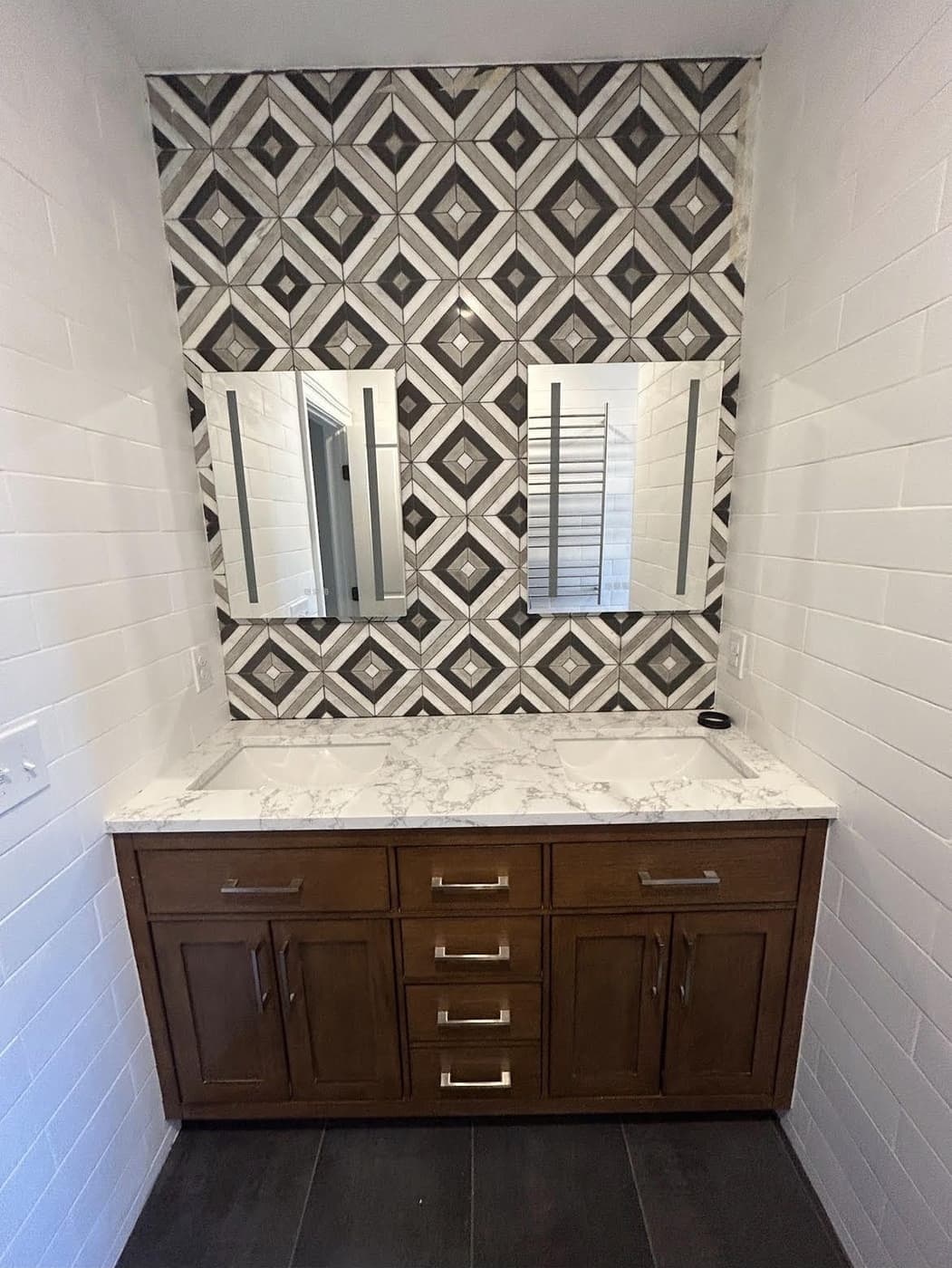 Double vanity below a bold black-and-white geometric tile accent wall