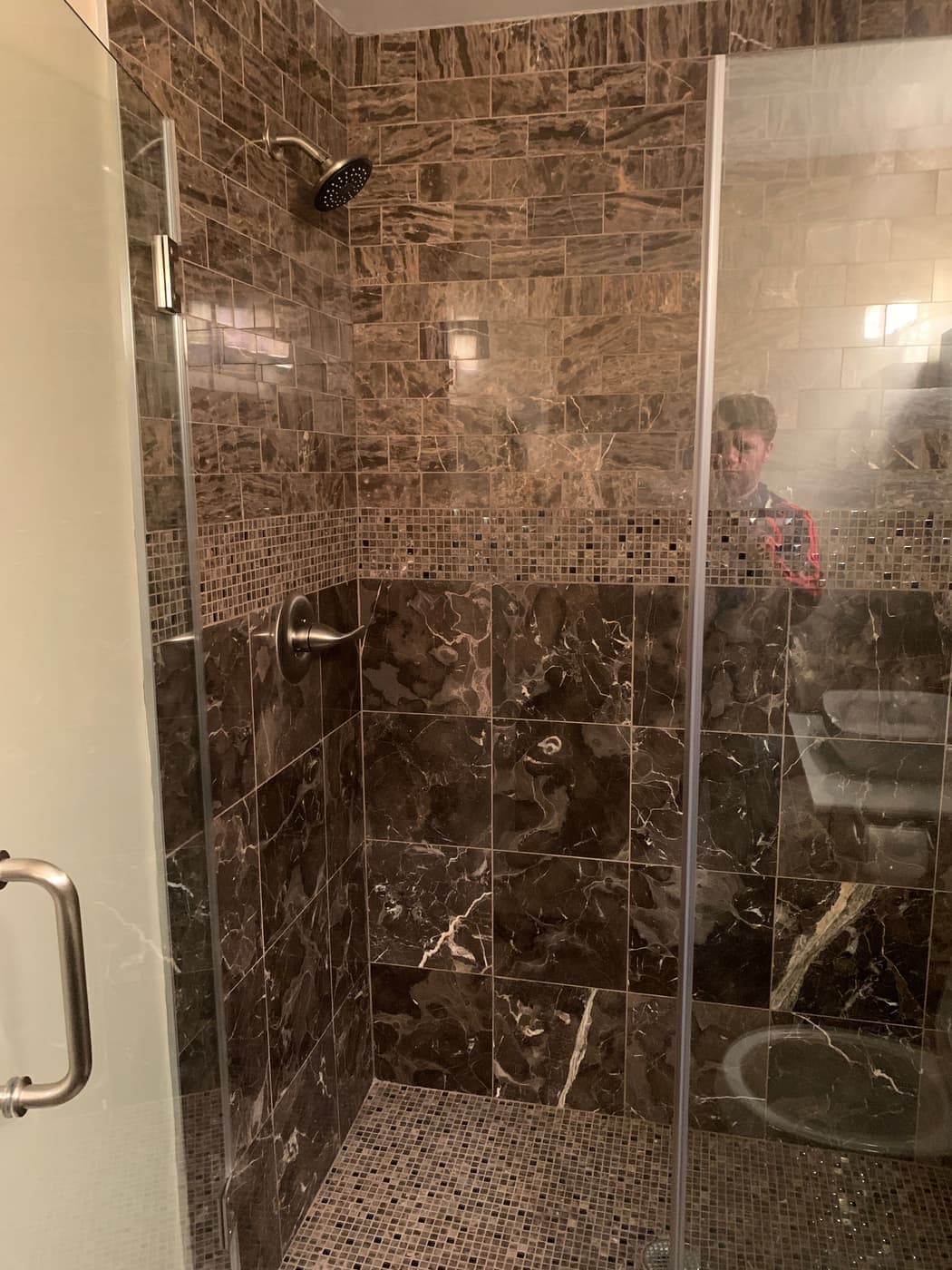 Walk-in shower with marble-look tile and a glass door