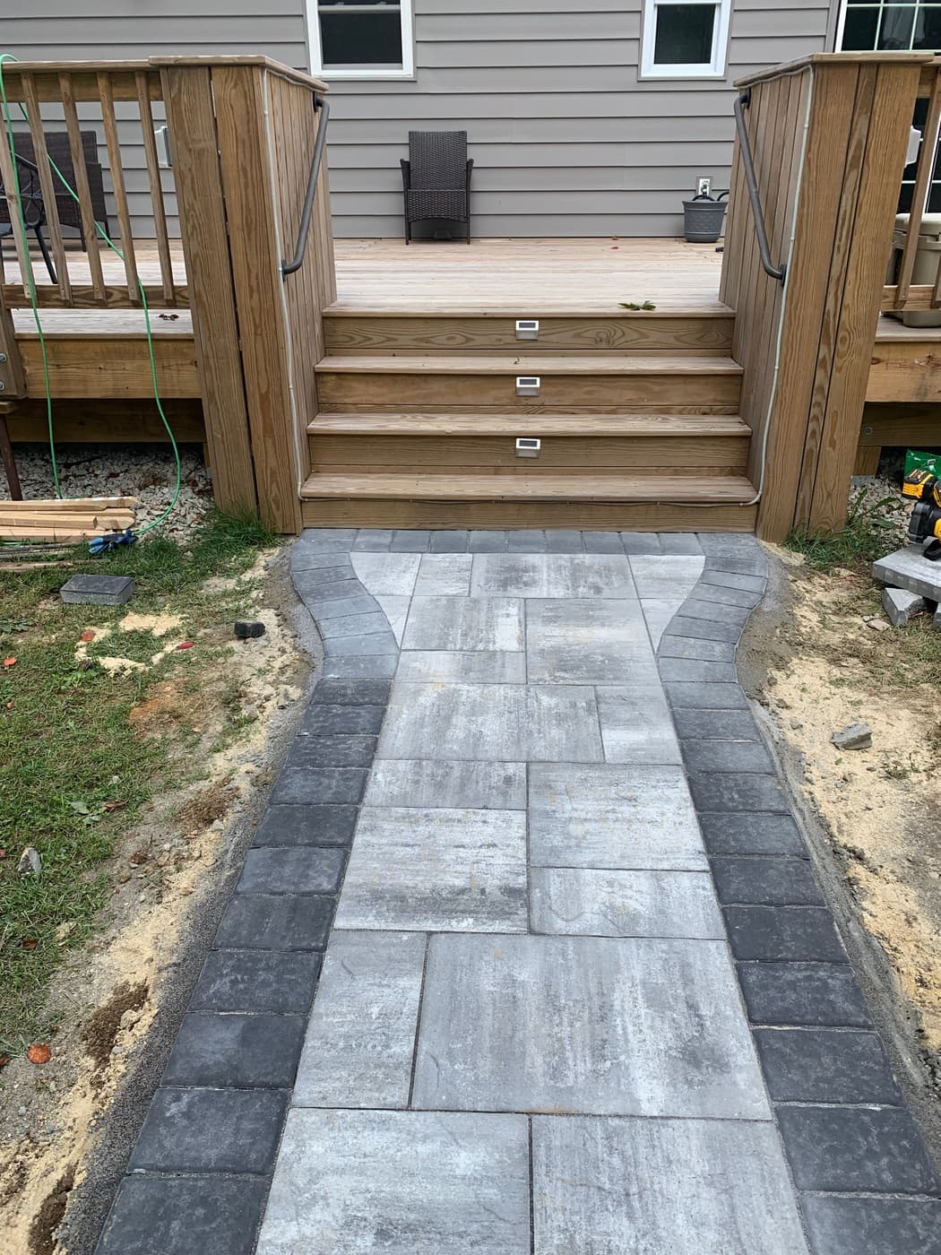 Gray paver walkway leading to wood deck steps