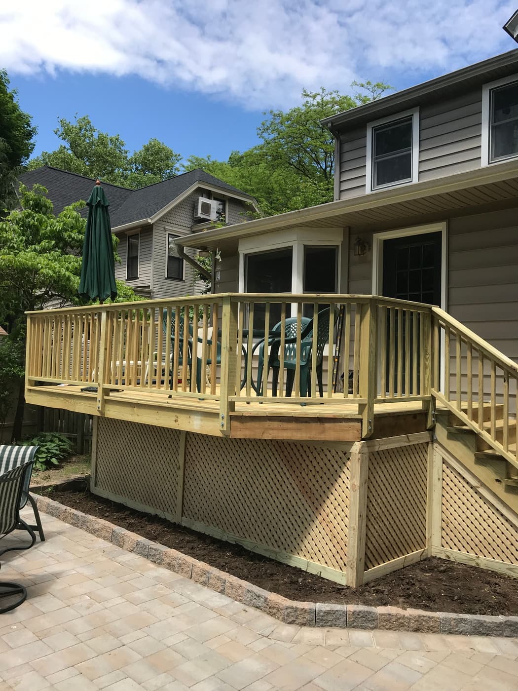 Raised wood deck with a pergola above a paver patio
